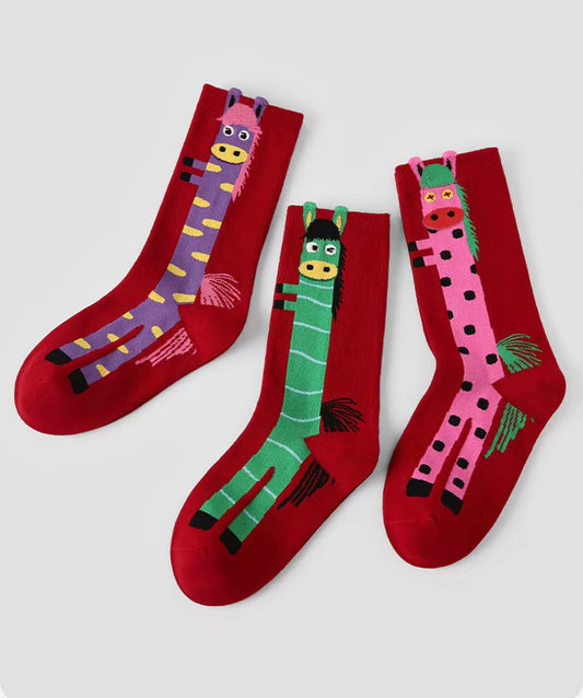 Year of Horse socks pack featuring three red socks with playful horse designs in purple, green, and pink